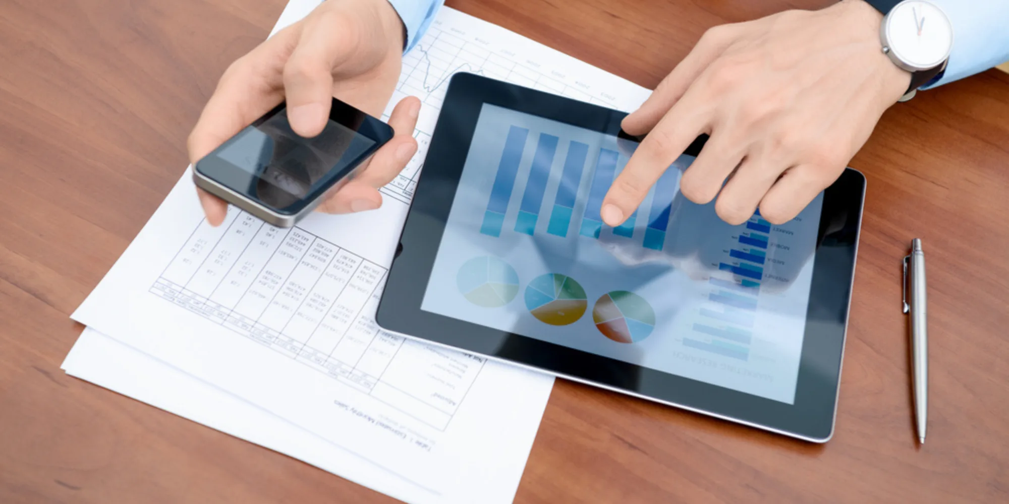Accounting Services | A person using an iPad and iPhone to review monthly stats.